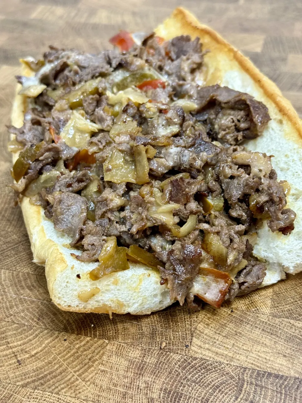 An open-face Philly cheesesteak on an East Coast hoagie roll